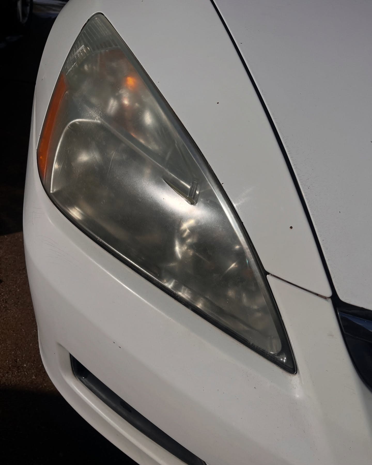 Before headlight restoration — hazy, oxidized lens on a white sedan, Adams Detailing Cumming GA