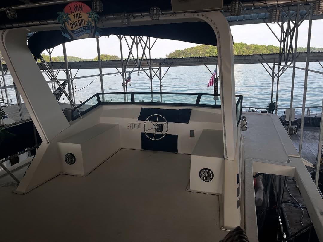 Spacious flybridge deck of a houseboat with steering console and canvas top, Lake Lanier marina