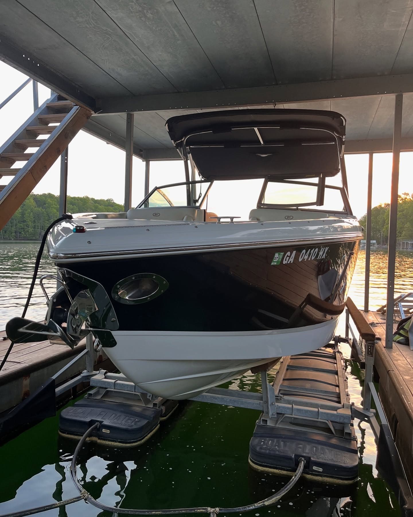 Detailed dark-hulled runabout on a covered boat lift at a Lake Lanier marina at dusk