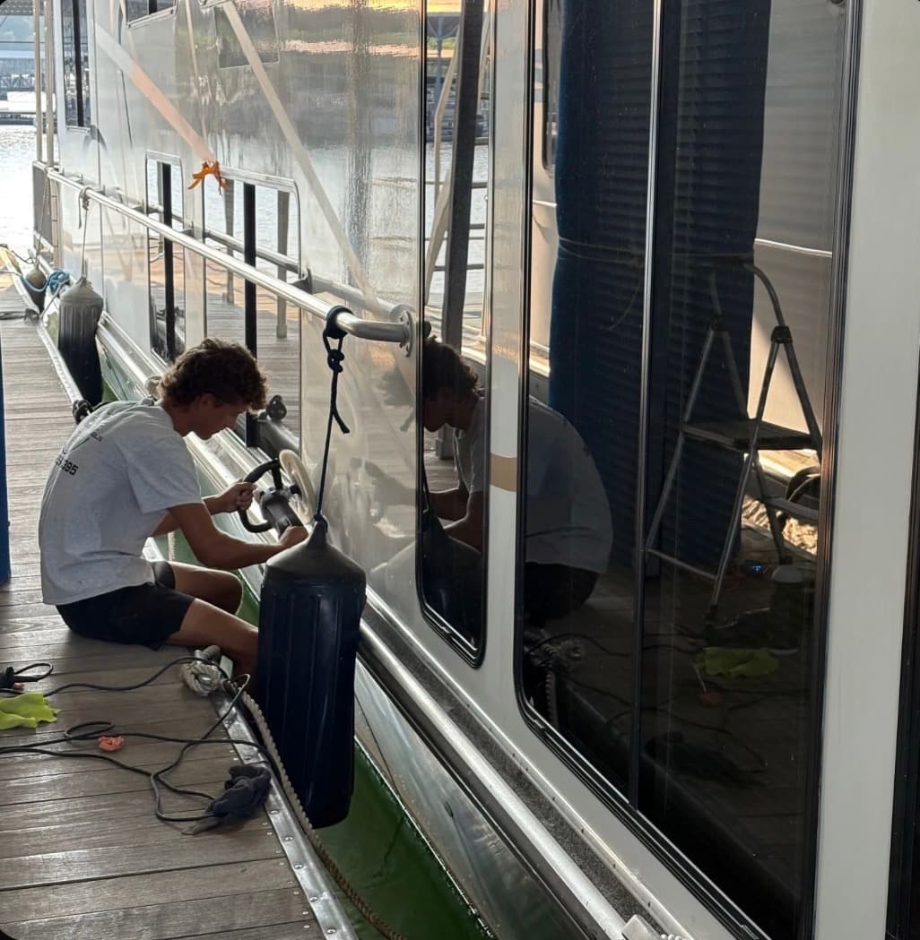 Peyton Adams polishing a houseboat dockside at a Lake Lanier marina, GA